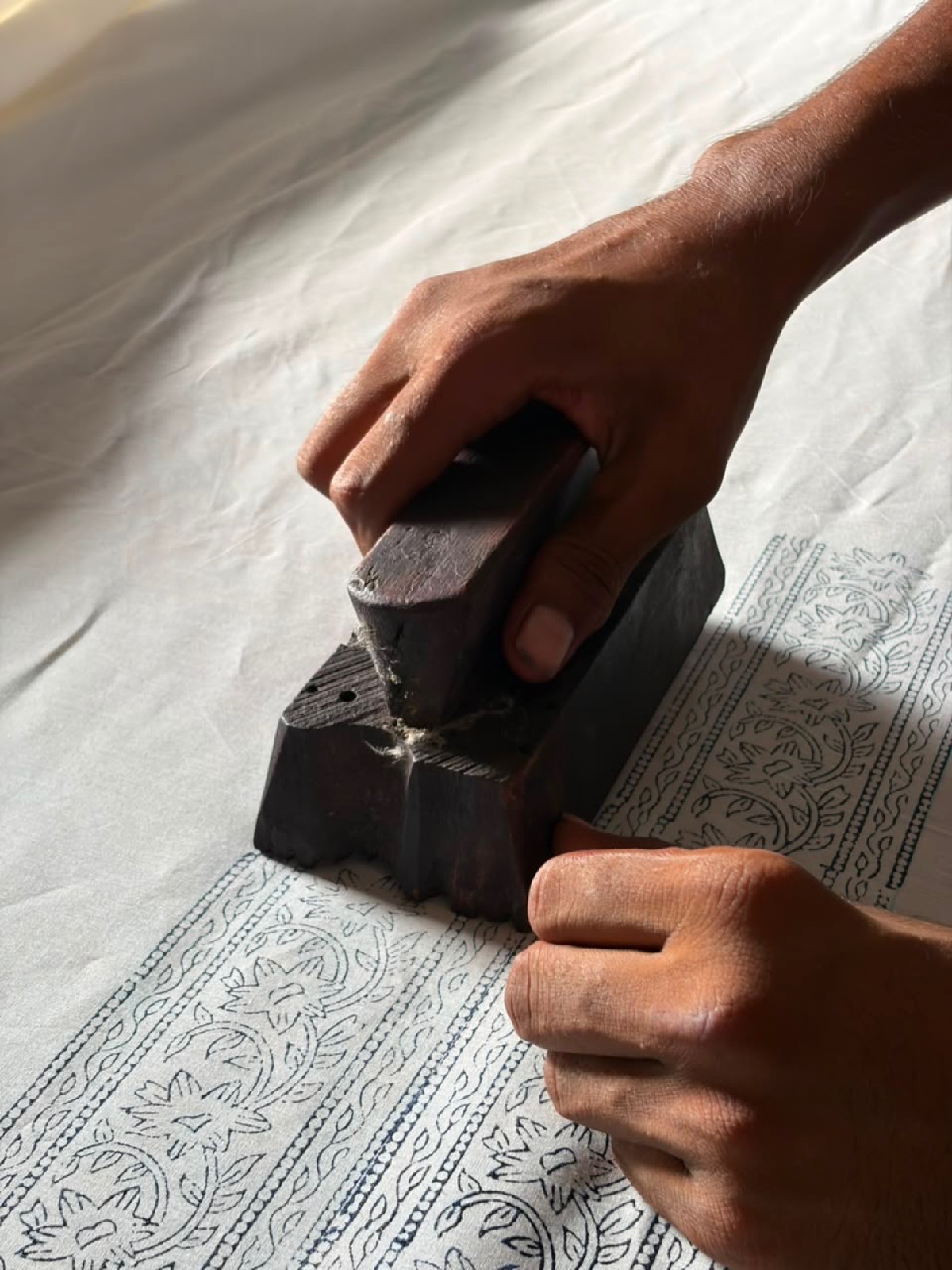Hands block-printing cotton by hand