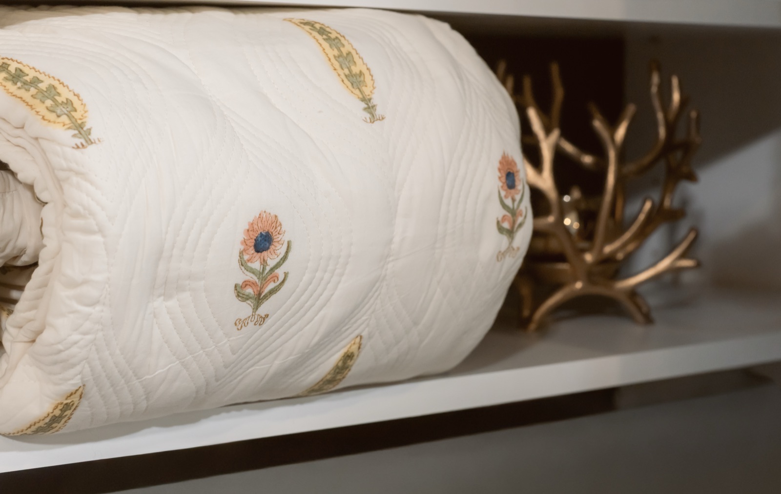 Block-print quilted bolster with brass coral detail